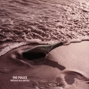 A bottle is in the water on the beach.