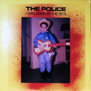 A young boy holding a guitar in front of a yellow background.