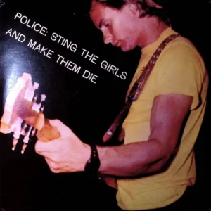 A man holding a guitar in front of a wall.