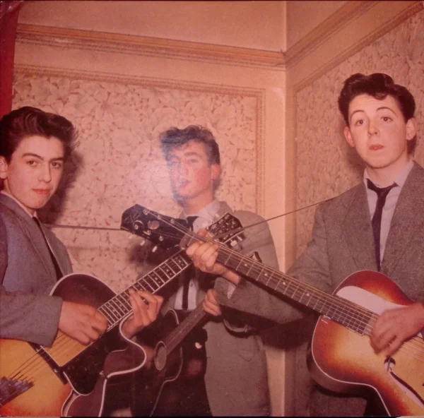 A group of young men playing guitars in a room.