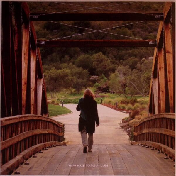 Woman walking across wooden bridge.