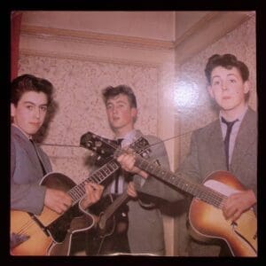 Young Beatles playing guitars together.