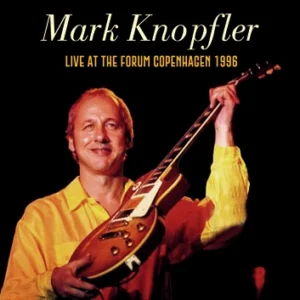 Musician holding guitar on stage, 1996 performance.