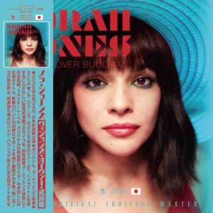 Album cover featuring a close-up of a woman with dark hair and bangs, set against a blue background.